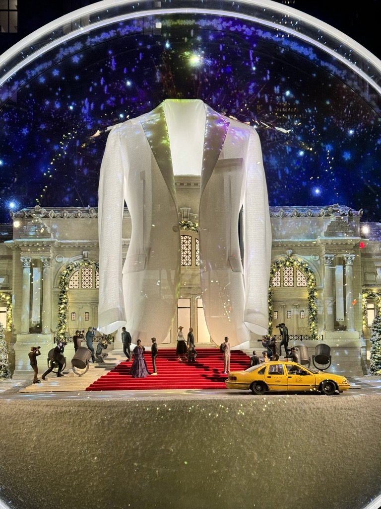 Dior window display with glowing jacket and miniature red carpet